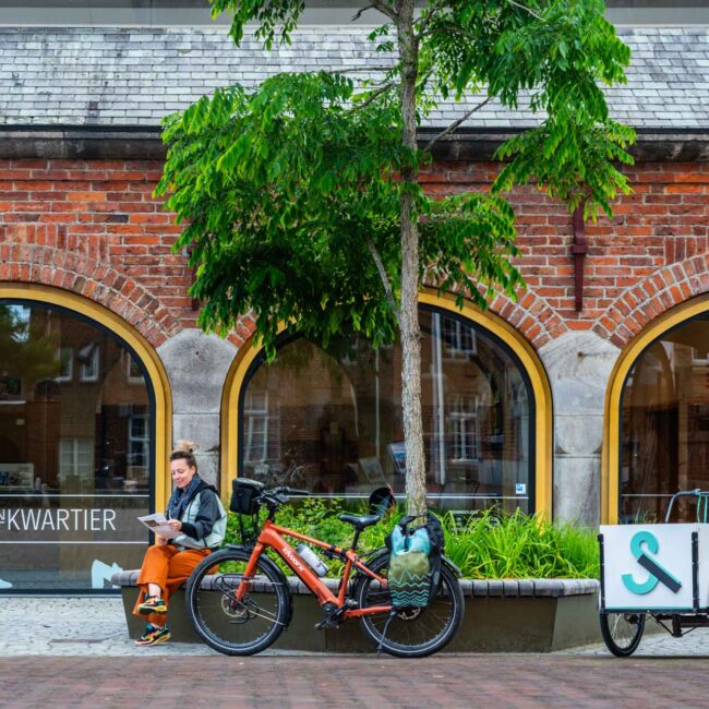 Een fietser rust uit voor het Schoenenkwartier in Waalwijk, over de voormalige leer- en schoenenindustrie van Waalwijk.