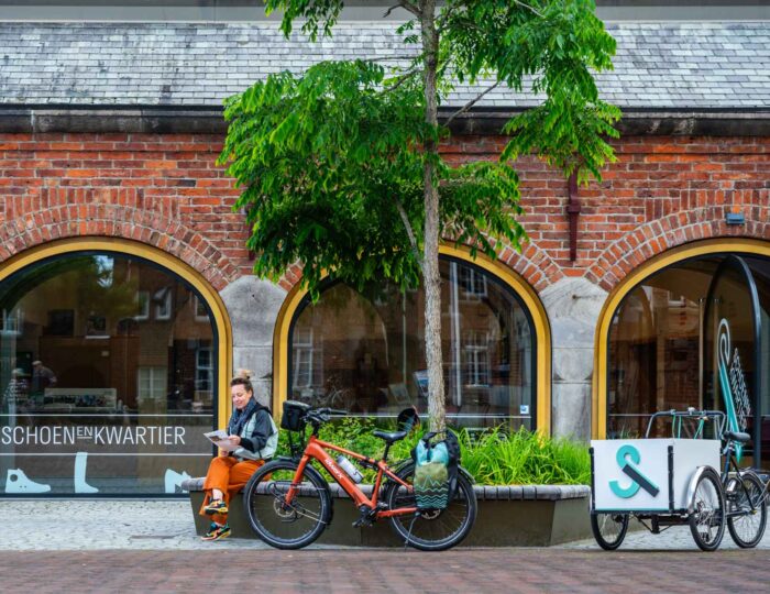 Een fietser rust uit voor het Schoenenkwartier in Waalwijk, over de voormalige leer- en schoenenindustrie van Waalwijk.