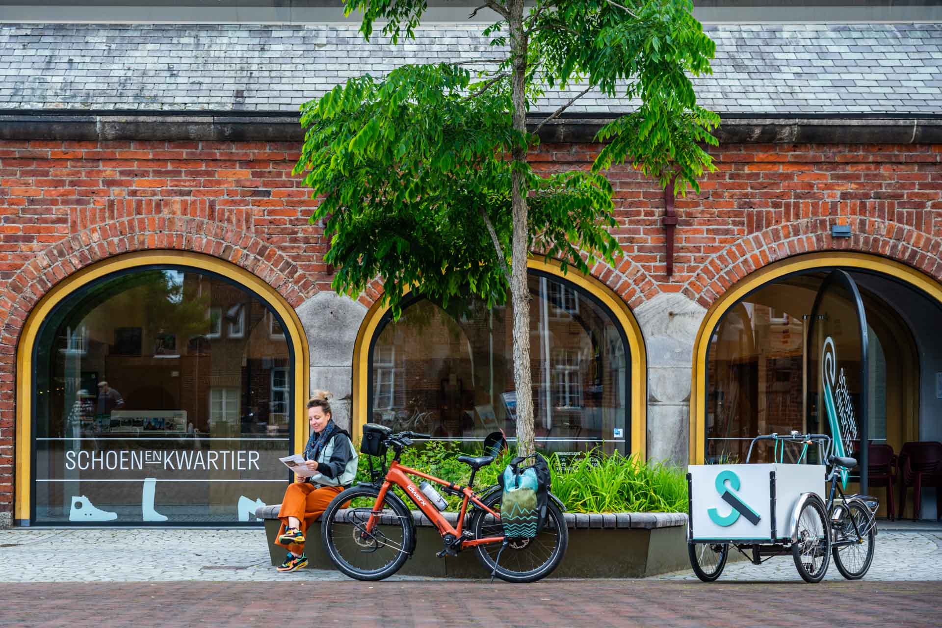 Een fietser rust uit voor het Schoenenkwartier in Waalwijk, over de voormalige leer- en schoenenindustrie van Waalwijk.