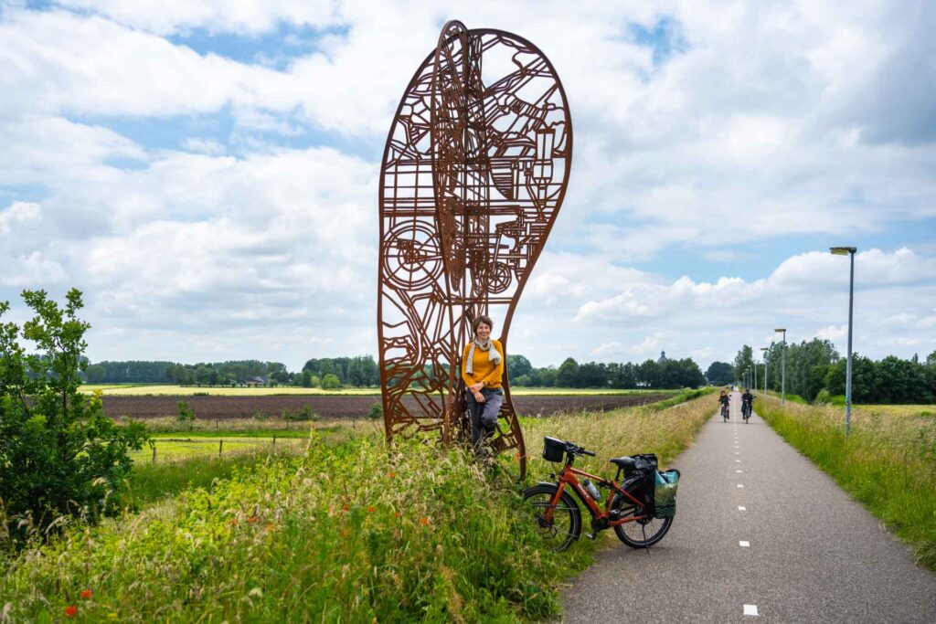 Fietser bij kunstwerk Footprint van kunstenaar Harald Vlugt op het Halve Zolenpad, een fietspad op een voormalig treinspoor bij Raamsdonk.